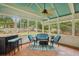 Screened porch with bar seating, cushioned wicker furniture, fan and tile flooring overlooking the backyard at 4624 Stonehenge Dr, Atlanta, GA 30360