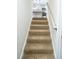 Carpeted stairs leading to open kitchen with island and stainless steel appliances at 6050 Randy Ln, Ellenwood, GA 30294