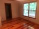Bedroom with hardwood floors, neutral walls, a dark trim, and a large window with a wooded view at 4744 Chickasaw Se Way, Acworth, GA 30102