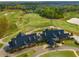 Aerial view of golf course featuring lush green fairways, a pond, and a clubhouse with ample parking at 508 Windy Ridge Ct, Canton, GA 30114