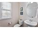 Small bathroom features a toilet and a pedestal sink next to a bright window at 2367 Millhaven Se St, Smyrna, GA 30080