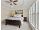 This bedroom features a brown leather bed frame, tray ceiling, ceiling fan, and natural light from large windows at 2367 Millhaven Se St, Smyrna, GA 30080