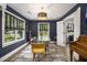 Dining area with modern chandelier, glass table and stylish decor featuring navy walls and wooden floors at 3135 Bluebird Ln, Decatur, GA 30032