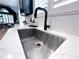 Close-up of a stainless steel kitchen sink with a modern black faucet and white marble countertops at 3804 Bay Orchard Lane, Loganville, GA 30052