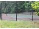 Tennis court surrounded by trees and a black chain link fence offers a private and serene playing environment at 3828 Woodridge Way, Tucker, GA 30084