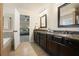 Bathroom featuring double sinks, dark wood cabinets, granite counters, and a view to bedroom at 132 Cornerstone Pl, Woodstock, GA 30188