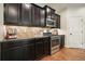 Close-up of kitchen features dark cabinets, stainless steel appliances, tile backsplash, and hardwood flooring at 132 Cornerstone Pl, Woodstock, GA 30188