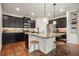 Well-lit kitchen with dark cabinets, stainless steel appliances, granite countertops, and a center island with bar stools at 132 Cornerstone Pl, Woodstock, GA 30188