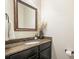 Elegant powder room featuring a granite countertop, decorative mirror, and stylish fixtures at 132 Cornerstone Pl, Woodstock, GA 30188