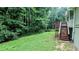 Spacious backyard including stairs leading to a porch, surrounded by mature trees and greenery at 3900 Ferncliff Rd, Snellville, GA 30039