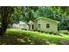 Charming single-story home featuring a stone accent wall, lawn, and a backdrop of lush trees at 3900 Ferncliff Rd, Snellville, GA 30039