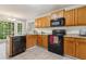 Traditional kitchen featuring wooden cabinets, black appliances, and granite countertops with natural lighting at 3902 Robin Court Ct, Acworth, GA 30101