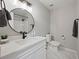 Modern bathroom features a round mirror and a white vanity with marble countertops at 5870 Shadewater Dr. Dr, Cumming, GA 30041