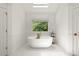 Bright bathroom featuring a soaking tub and a large window with a lush view at 4392 Windsor Oaks Cir, Marietta, GA 30066