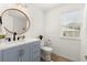 Well-lit bathroom featuring a blue vanity, modern fixtures, and a stylish round mirror at 4392 Windsor Oaks Cir, Marietta, GA 30066