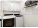 A functional laundry room with modern washer and dryer units, storage cabinets, and shelving for supplies at 4392 Windsor Oaks Cir, Marietta, GA 30066