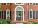 Elegant brick home featuring a classic arched doorway, black shutters, and manicured landscaping at 4955 Day Lily Nw Way, Acworth, GA 30102