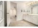 Bathroom with dual sink vanity, open doorway leading to the bedroom, white carpet and walls with bright lighting at 80 Stratford Ne Pl, Atlanta, GA 30342