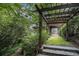 Idyllic garden path with wooden pergola and stone steps, surrounded by lush greenery and mature trees at 80 Stratford Ne Pl, Atlanta, GA 30342