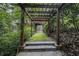 Enchanting garden path with a wooden pergola, leading through lush greenery and moss-covered steps at 80 Stratford Ne Pl, Atlanta, GA 30342