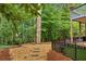 Beautiful backyard with stone pavers, black metal fencing, mature trees, and an upper deck overlooking the landscape at 878 Treadstone Overlook, Suwanee, GA 30024