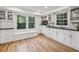 Bright kitchen features white cabinets, hardwood floors, and a large window with a window seat overlooking a wooded area at 1151 Roxboro Ne Cv, Atlanta, GA 30324