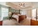 Main bedroom with trey ceilings, ceiling fan, many windows, and plush carpeting at 1461 Radstone Dr, Lawrenceville, GA 30044
