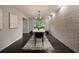 Modern dining room featuring a light wood table with black chairs, hardwood flooring, and a textured brick wall at 4214 Williamsburg Dr, College Park, GA 30337