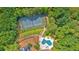 Aerial view features a tennis court, kidney-shaped pool, home, and driveway nestled amongst lush, green trees at 52 Waterside Se Dr, Cartersville, GA 30121