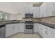 Modern kitchen features stainless steel appliances, white cabinets, and dark countertops, seamlessly flowing into the living space at 6468 Panasa Ct, Tucker, GA 30084