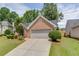 Brick home with a two car garage on a lush green lot with driveway and manicured bushes at 2420 Walnut Grove Way, Suwanee, GA 30024