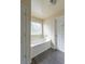 Bright bathroom featuring a soaking tub with a window and wood grain floors at 1336 Nathan Mauldin Dr, Lawrenceville, GA 30043