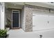 Close-up view of the front door and attached two-car garage and well manicured front yard at 7814 Messina Ct, Lithia Springs, GA 30122