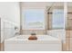 Elegant bathtub with stylish tile surround and window view creates a relaxing retreat at 6825 Rambling Vale, Cumming, GA 30028