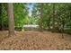 Wooded backyard with pine straw and trees, featuring a house with a fenced perimeter at 747 Channing Nw Dr, Atlanta, GA 30318