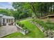Landscaped backyard featuring a brick patio, stone retaining wall, lush lawn, and a charming fence line at 747 Channing Nw Dr, Atlanta, GA 30318