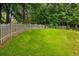 Wide backyard with a spacious green lawn, surrounded by a white fence and mature trees at 747 Channing Nw Dr, Atlanta, GA 30318