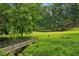 Green community space with a metal bridge over a small creek, mature trees, green grass, and a picnic table at 747 Channing Nw Dr, Atlanta, GA 30318