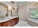 Bathroom featuring wood cabinets, dual sinks, and marble tile with a soaking tub at 1676 Grove Park Way, Decatur, GA 30033