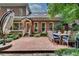 Back patio featuring wood chairs, a large umbrella, brick-and-stone surfaces, and manicured foliage at 1676 Grove Park Way, Decatur, GA 30033
