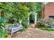 Serene side yard featuring a wooden bench, arbor, gravel path, and lush plantings at 1676 Grove Park Way, Decatur, GA 30033