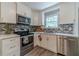 Close up of a kitchen with stainless steel appliances, white cabinetry, and a black and gray backsplash at 2645 Holly Berry Trl, Snellville, GA 30039