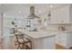 A modern kitchen is enhanced with white cabinets, stainless hood, granite counters and breakfast bar seating at 4016 Dover Ave, Alpharetta, GA 30009