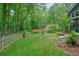 Large backyard with grass, mature trees, a fire pit area with chairs, and a wooden fence at 588 Benson Hurst Dr, Mableton, GA 30126
