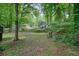 Large and wooded backyard, with mature trees surrounding the property and a lawn and shed at 588 Benson Hurst Dr, Mableton, GA 30126