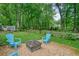 Backyard with a fire pit, gravel, adirondack chairs, grass and mature trees offering a great outdoor space at 588 Benson Hurst Dr, Mableton, GA 30126