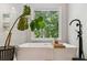 Bright, modern bathroom with a soaking tub and a large window looking out on the property's nature at 7235 Compton Cir, Cumming, GA 30040