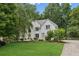 Stunning two-story white brick home with lush landscaping, mature trees, and a well-manicured lawn at 7235 Compton Cir, Cumming, GA 30040