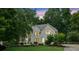 Beautiful white brick home with inviting curb appeal surrounded by lush, mature trees at dusk at 7235 Compton Cir, Cumming, GA 30040