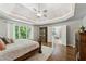 Bright main bedroom features a tray ceiling, hardwood floors, and view of the private backyard at 7235 Compton Cir, Cumming, GA 30040